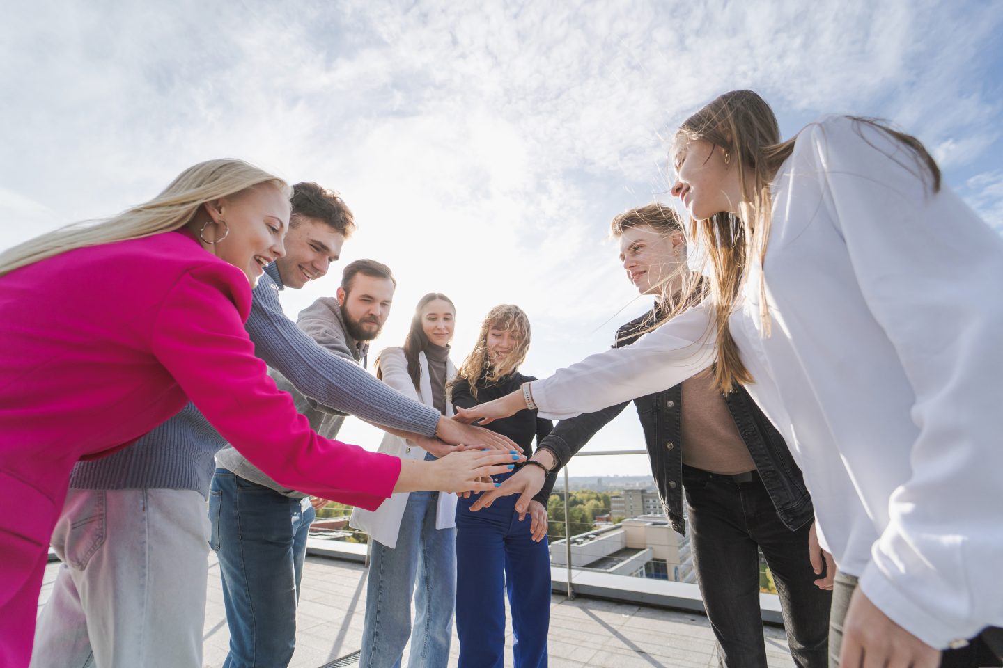 Studentai sudėję rankas kaip komanda
