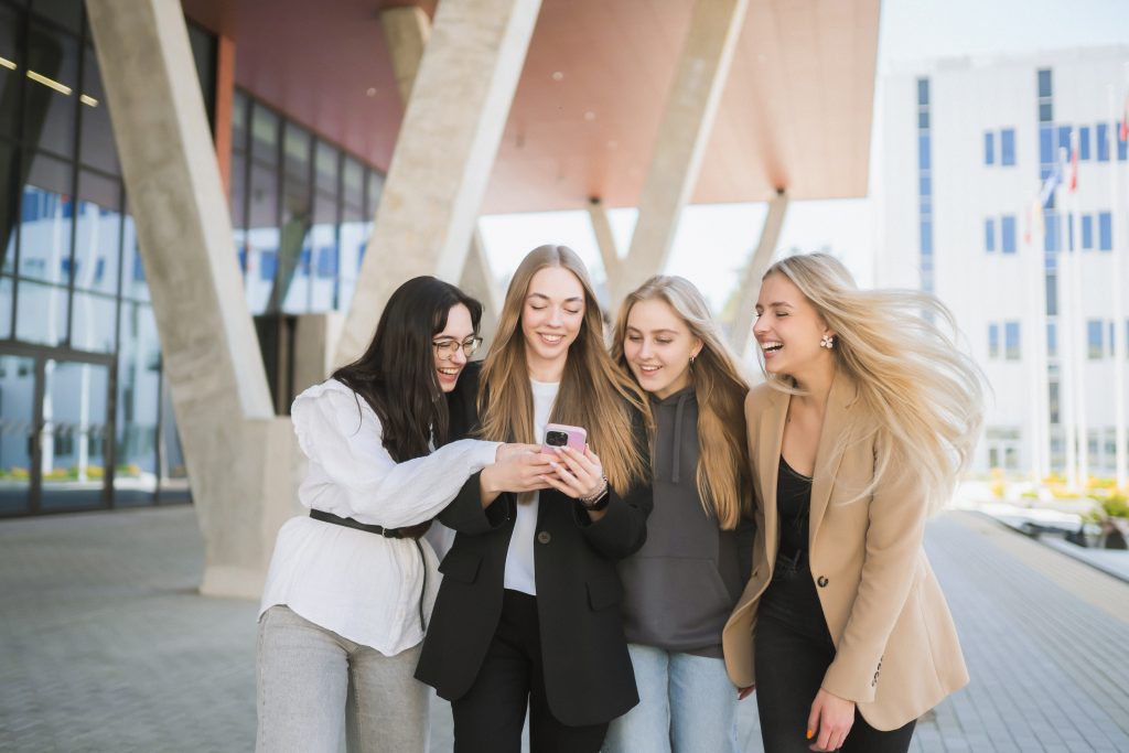 Studentai žiūri į telefoną
