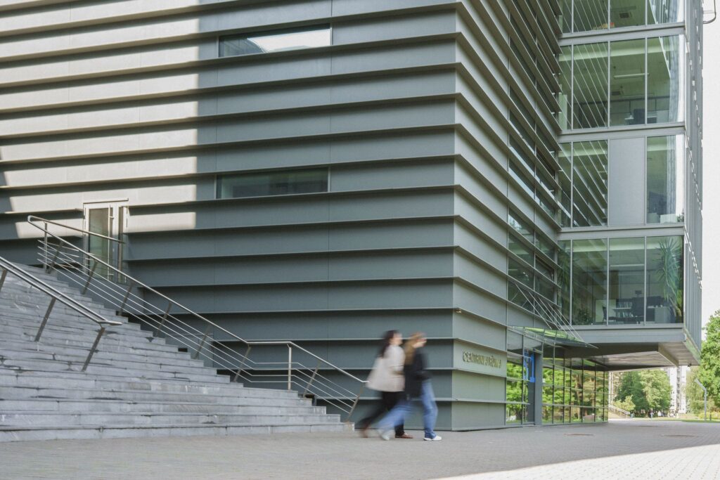 Studentai eina šalia universiteto pastato