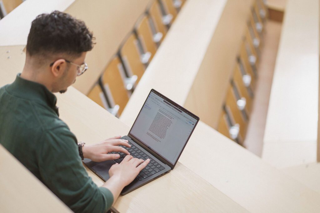 Studentas dirba kompiuteriu tuščioje auditorijoje